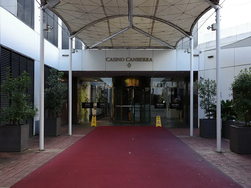 Covered entrance to Casino Canberra with a red carpet walkway and potted plants